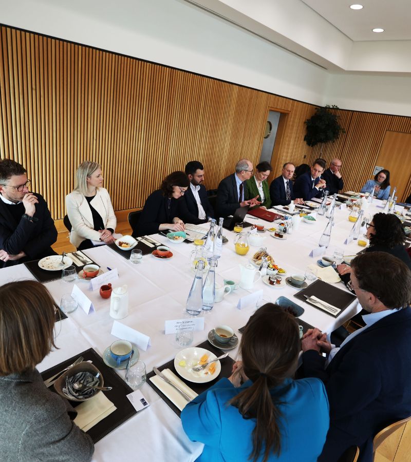 Lord Vallance attends roundtable discussion in Oxford. Delegates sit around a wooden table.
