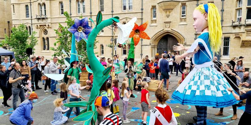 Picture of Broad Meadow showing a large Alice in Wonderland puppet entertaining children in the space.