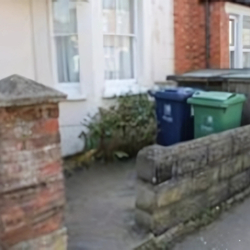 Example of incorrect bin presentation showing blue and green bins positioned on property which collection crews would need to walk on to collect