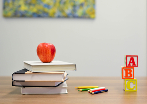 Apple on book with pens and blocks